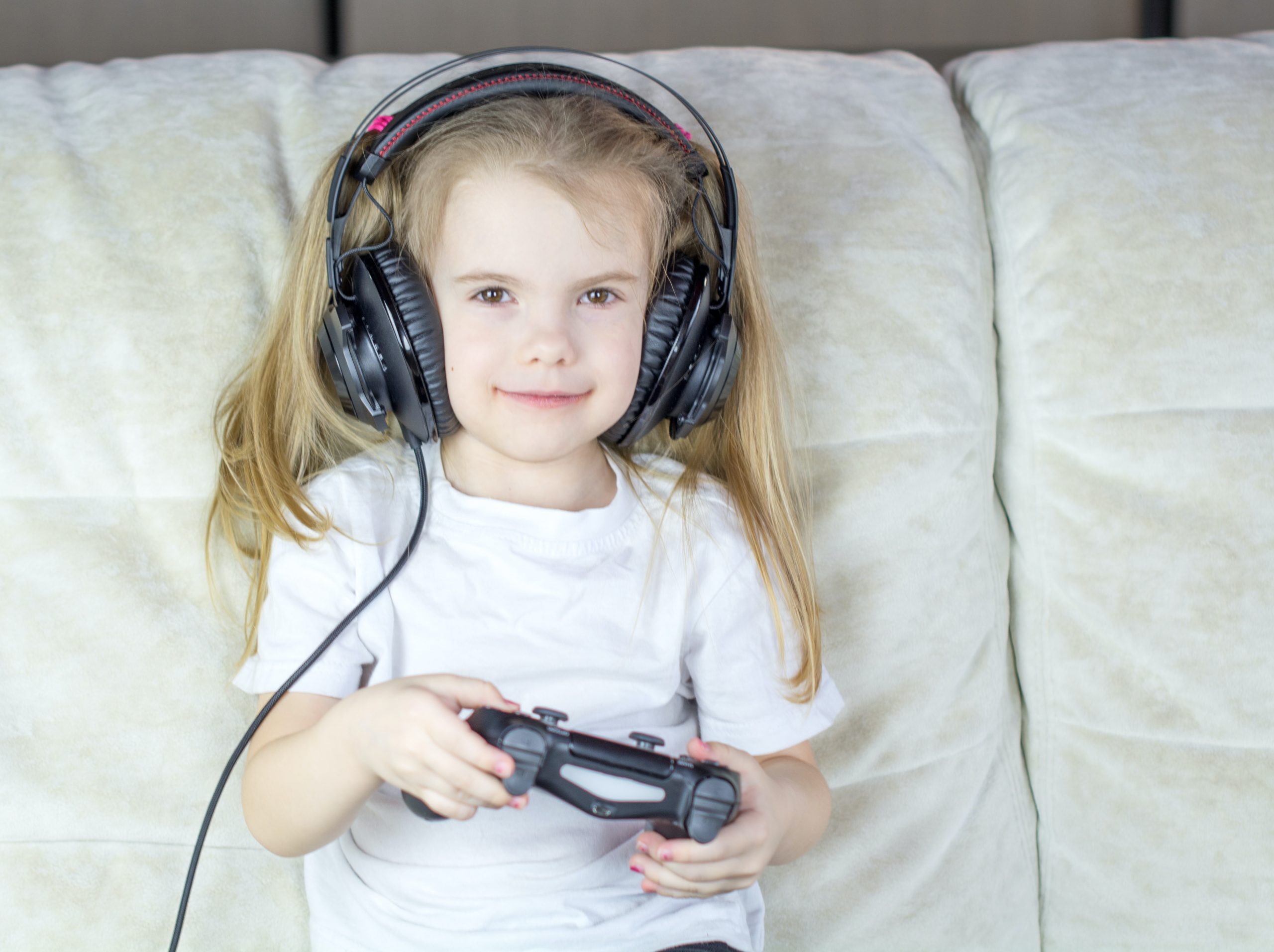 Kind mit Kopfhörern und Craddle zocken Spiel Playstation Konsole Medien